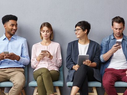 People sit in a waiting room, each focused on their phone