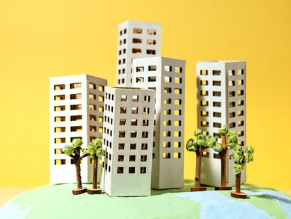 A paper-crafted Earth is adorned with tiny paper buildings, offering a whimsical take on a global landscape