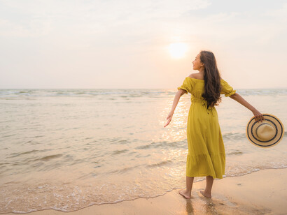 A woman immersed in the glow of sunset at the beach, mirroring the introspective spirit of travel