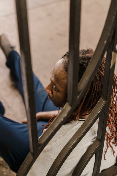 A man sat on the floor leaning against a railing
