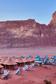 A desert landscape with traditional Bedouin tents and surrounding mountains can be seen in Wadi Rum, Jordan
