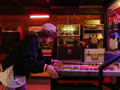 Criança em fliperama brinca ao mesmo tempo que controla uma máquina