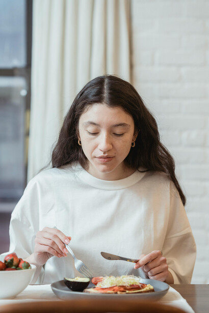 Woman eating a healthy breakfast using a fork and knife