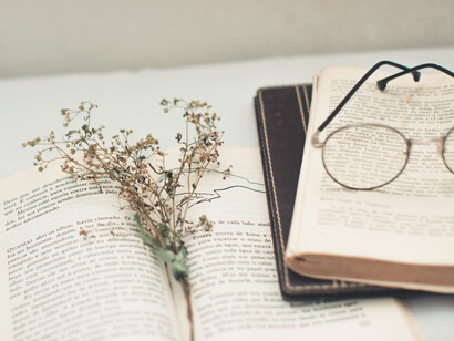 Una escena conocida para los poetas: gafas y libros sobre un escritorio