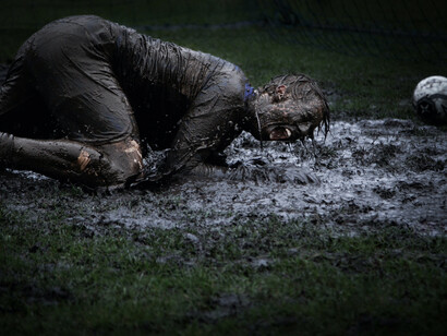 Un portero cae en el barro tras detener un disparo
