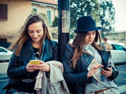 Dos amigas chateando con sus teléfonos móviles