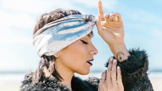 A woman wearing several rings and earrings, eyes closed