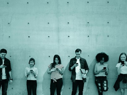 Uomini e donna davanti allo schermo dello smartphone: "Oggi, invece, i bambini si isolano davanti a uno schermo, comunicando con amici virtuali che non hanno mai incontrato. Siamo più connessi che mai, ma la connessione umana, quella vera, sembra essersi spezzata"