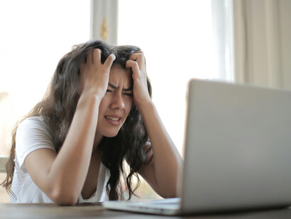 A young woman on her laptop at home, overwhelmed by digital anxiety, nonstop information, and the stress of scrolling through negative news