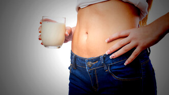 A woman with stomach problems drinking probiotic shots