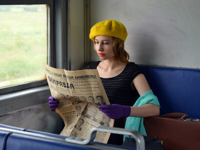 No vagão, a atriz lê uma matéria no jornal sobre perseguições políticas