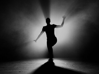 Inteiro sob o foco de luz, o bailarino sustenta uma pose que parece suspender o tempo. A maturidade, no texto, também é esse aprendizado: reconhecer o que permanece quando todas as formas ao redor se transformam. Talvez seja assim que algumas verdades da vida se revelam: não no excesso de movimento, mas naquilo que permanece quando tudo silencia