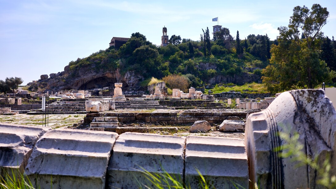 Sito archeologico del santuario di Demetra a Eleusi. Il cortile del santuario a sinistra, sopra la scalinata i Propilei Maggiori. Accanto alla caverna sullo sfondo si trovava il santuario di Plutone: la caverna rappresenta l'ingresso agli Inferi. Il sentiero a sinistra della caverna conduce al Telesterion, dove i fedeli venivano iniziati ai misteri eleusini. Eleusi, Grecia