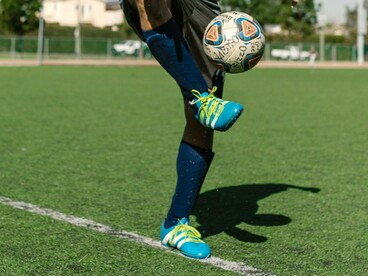 Crampons aux pieds, un joueur s'entraîne et s'amuse avec le ballon