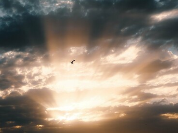 A luz do sol rompe a formação de nuvens densas no céu. Assim como a claridade que surge entre as sombras, a busca pela verdade pode atravessar as convenções que tornam a realidade mais confortável e previsível