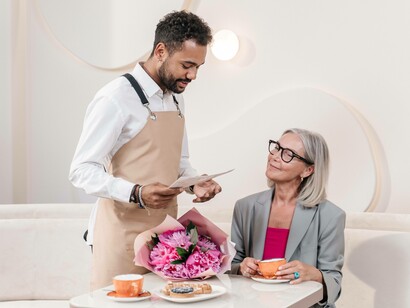 A waiter is winning the customer at the restaurant over with his hospitality charm 