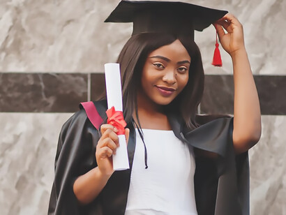 A young female student proudly strikes a pose, clutching her diploma, a symbol of her academic achievement and determination