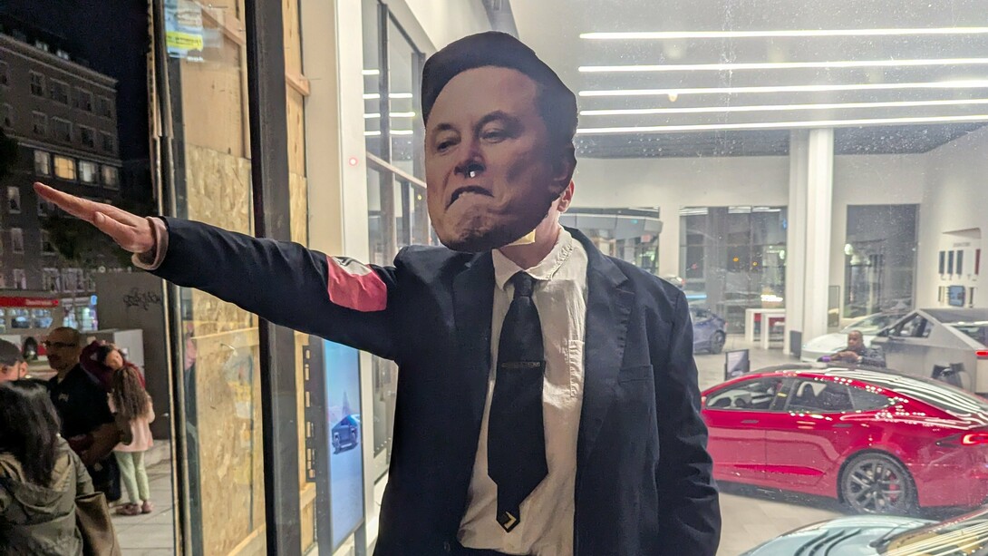 Manifestante faz referência ao gesto de Elon Musk durante a posse de Donald Trump. Ao realizar uma saudação nazista, Musk não apenas chocou o mundo, mas também reforçou a normalização de símbolos históricos de opressão, violência e autoritarismo. Musk gerou repercussões globais, incentivando extremistas ao redor do mundo e alimentando a retórica de grupos neonazistas, que enxergaram naquele ato uma validação de suas crenças. Não houve, porém, nenhuma responsabilização por seu ato