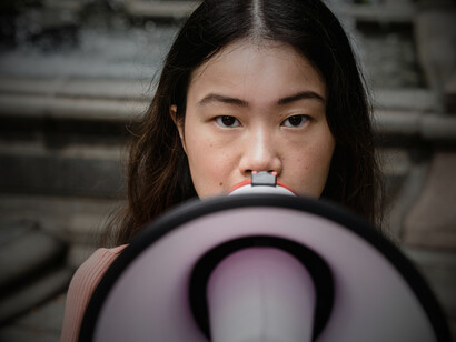 A young woman calling for action through a megaphone, mirroring growing youth engagement in diplomacy and advocacy