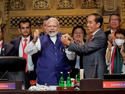 PM Narendra Modi and Indonesia's President Joko Widodo hold hands during the handover ceremony at the G20 Leaders' Summit in Nusa Dua, Bali, on 16 November 2022