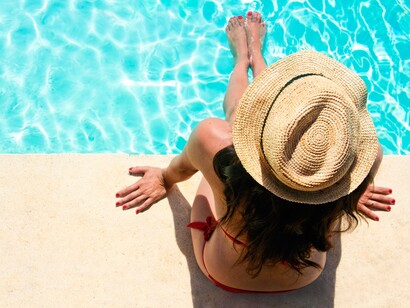 Una chica sentada al borde de la piscina