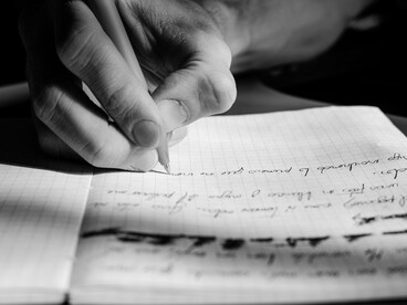 Una persona escribe en un cuaderno una serie de anotaciones, acompañadas de varios tachones
