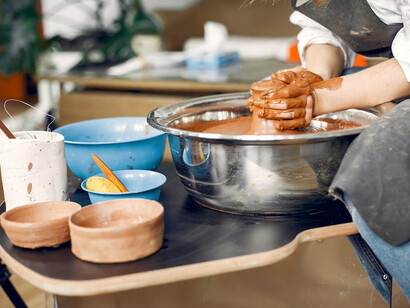 A close-up of a female potter crafting earthenware on a pottery wheel