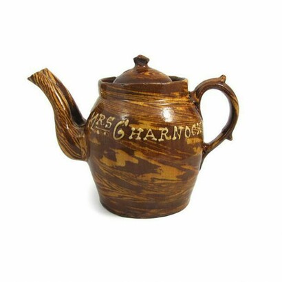Thrie Estaits, Double Spouted Teapot, 1899, Moulded, Marbled earthenware with sliptrail decoration ‘Newton Heath A Pig 1899 – Mrs Charnock.’ This is most likely to have been a mass produced teapot from the Potteries of Stoke-on-Trent