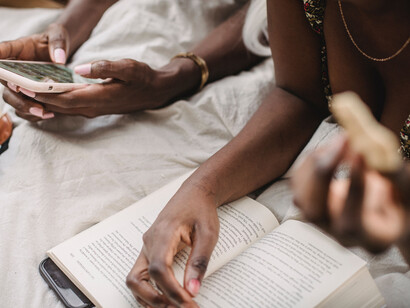 Amigas leem juntas o mesmo livro físico em versão física e digital
