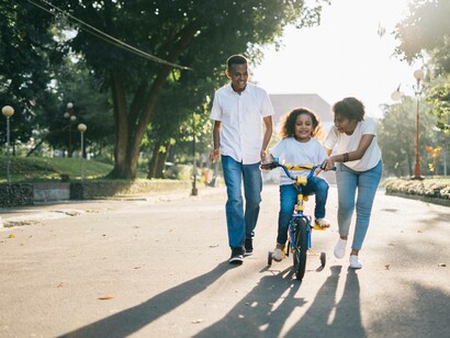 A family of three teaching their child how to ride a bike