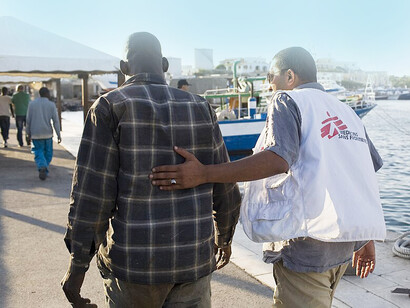 Migranti. A terra, dopo il triage da parte dell'equipaggio di Medici Senza Frontiere, i nuovi arrivati vengono rapidamente caricati sugli autobus e traghettati al centro di accoglienza ricostruito un anno fa con i sussidi dell'Unione Europea, dove ai migranti vengono forniti vestiti puliti, scarpe e una scheda telefonica
