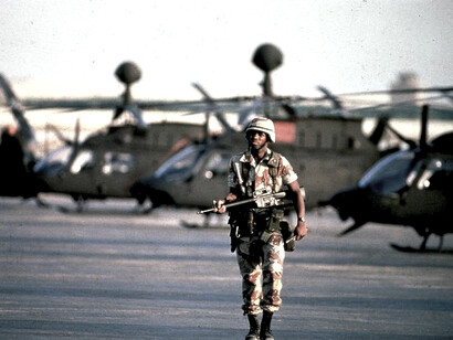 United States forces during the 1991 Gulf War: a sentry patrols alongside a line of OH-58 Kiowa helicopters at an American air base in Saudi Arabia
