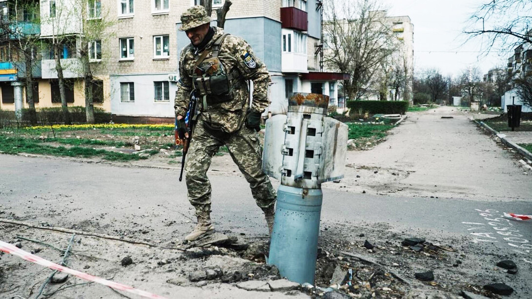 Soldado del Ejercito ucraniano caminando al lado de los restos de una bomba de guerra en Kiev, Ucrania
