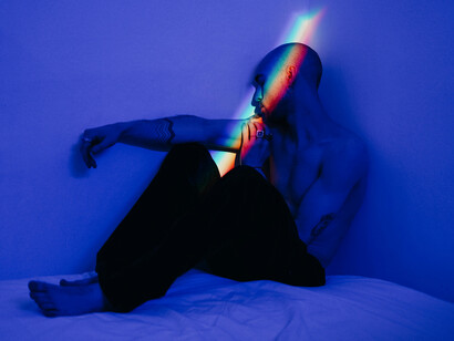 A downcast man sitting on his bed, a glimmer of hope flickers