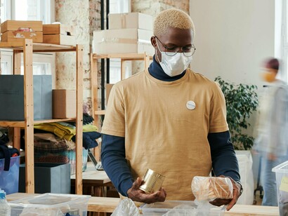 L'homme trie la nourriture dans différentes boîtes tout en maintenant les protocoles d'hygiène et de sécurité