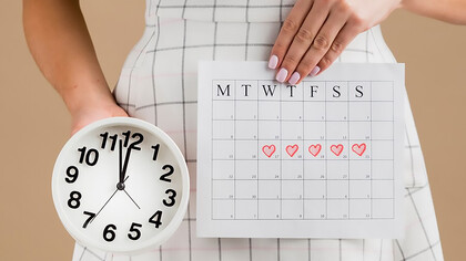 A woman holding a clock and calendar, symbolizing the importance of tracking menstrual health and cycle regularity
