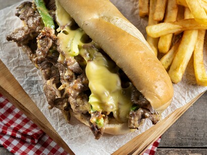 Originating in Philly, this iconic sandwich features tender steak, gooey melted cheese, and vibrant green peppers, served here with fries
