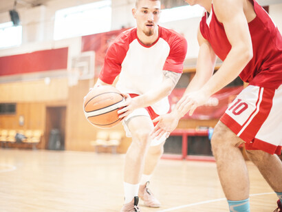 A man playing basketball in college with another player