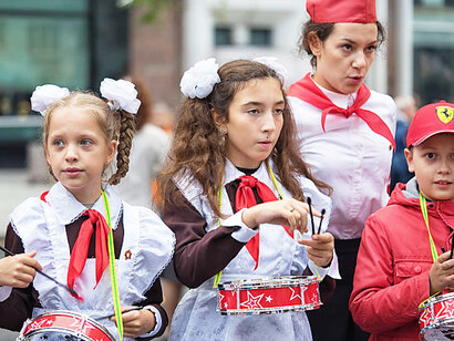 Children dressed in Soviet school uniforms playing drums as part of the Young Pioneers