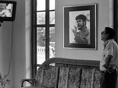 Hombre ve la televisión junto a una imagen enmarcada del líder político Ernesto "Che"
Guevara