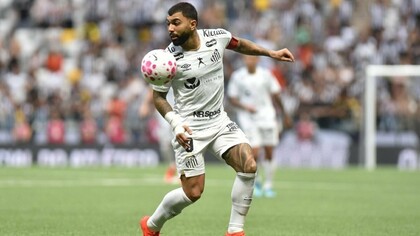 Com o corpo inclinado e os olhos fixos na bola, Gabigol participa de uma jogada vestindo a camisa branca do Santos. A postura do atacante revela a atenção necessária para dominar a bola e encontrar o melhor caminho para dar continuidade à ação, enquanto os jogadores ao fundo acompanham o lance. De volta ao clube que o revelou para o futebol profissional, Gabriel Barbosa encara o desafio de recuperar o protagonismo e demonstrar que ainda pode ser decisivo. Seu retorno desperta uma pergunta entre os torcedores: será que o reencontro com o Santos marcará o início de uma nova fase de grandes atuações? A resposta virá em campo