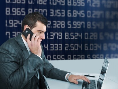Un trader observa su ordenador y habla por teléfono