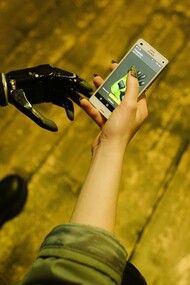 A person with a bionic arm holds a smartphone, illustrating the everyday integration of assistive technology