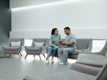 A conversation between a medic and patient in an empty waiting area, symbolising how access to healthcare often begins with waiting