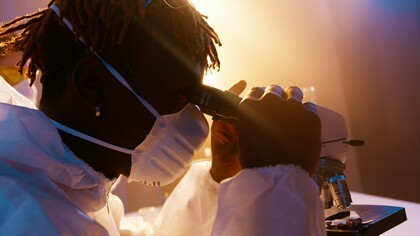 A scientist carefully examining a sample through a microscope, representing the pursuit of transcriptome research to advance human health