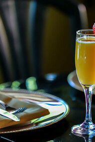 A champagne glass filled with a refreshing mimosa, accompanied by a vibrant brunch table set with delicious cocktails and food