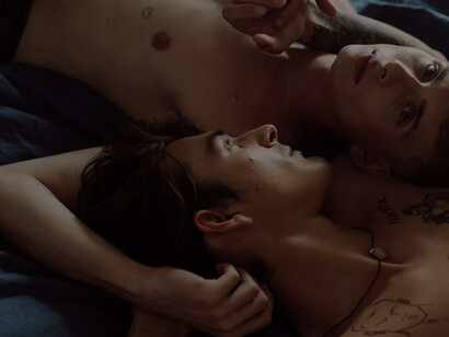 Two men in an intimate embrace in a cozy bedroom setting