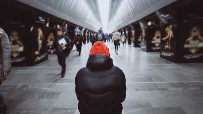 A view from behind of a man in a crowded subway, capturing the sense of alienation among commuters