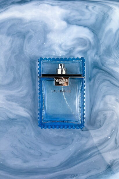 The iconic Eau Fraîche bottle surrounded by shimmering water, representing Versace’s approach to timeless luxury and style