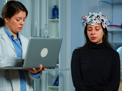 A woman researcher examining a brain scan on a monitor, utilizing artificial intelligence to enhance healthcare diagnostics and treatment plans